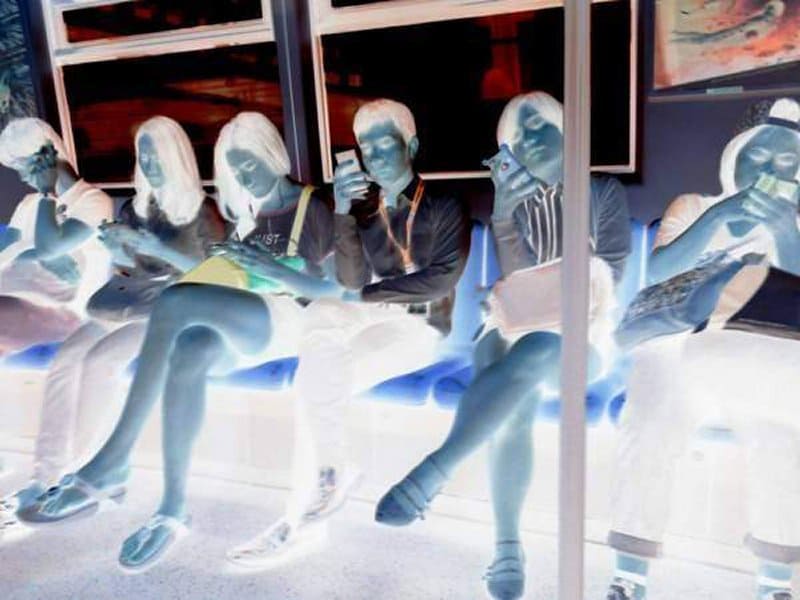 People sitting in public transport all looking at their mobile phones