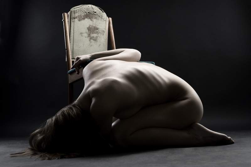 Naked woman curled up on the floor crying