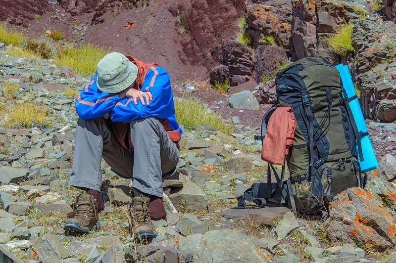 Backpacker sitting on a mountain exhausted