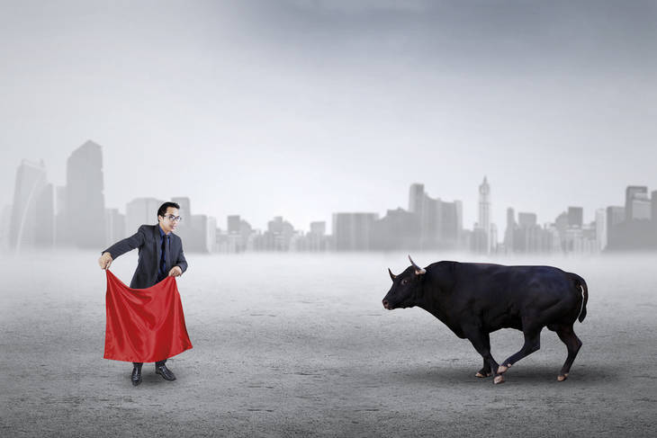 Businessman with red cloth facing bull - Don't be a "sacrificial cow"