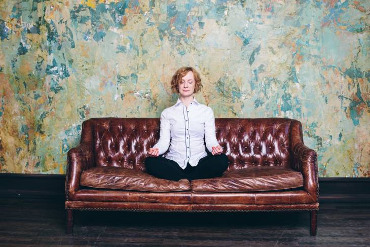 Woman sitting on couch doing breath guided meditation