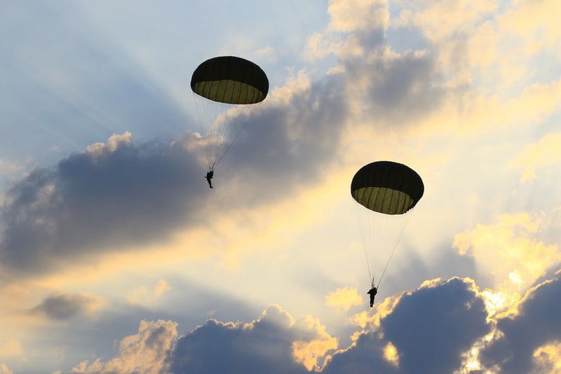 Parachutists in partly cloudy sky with sun rays