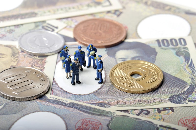 Plastic toy police standing on a selection of banknotes and coins