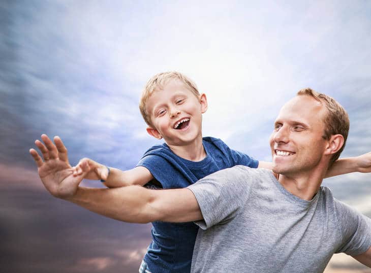 Smiling father and son against blue sky - Laugh your way to higher consciousness