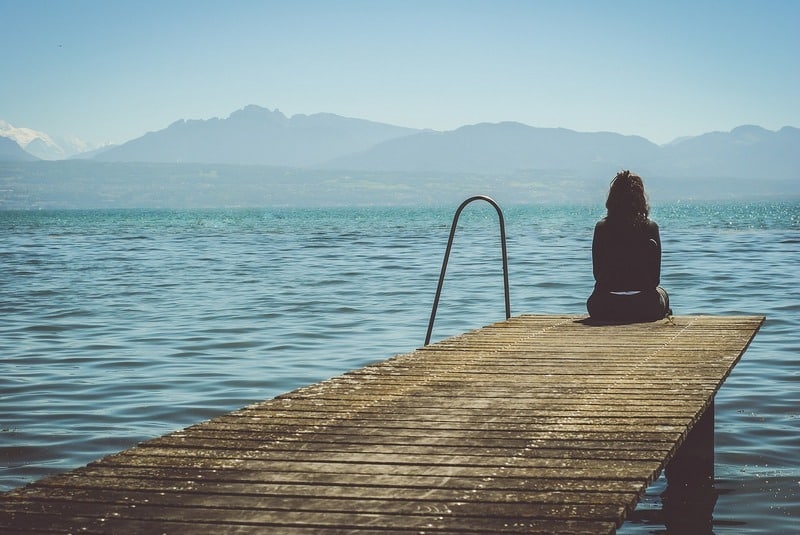 INNER JOURNEY: Finding the fearlessness to sit with ourselves and travel inward 13 Woman sitting alone on the end of a pier on a lake