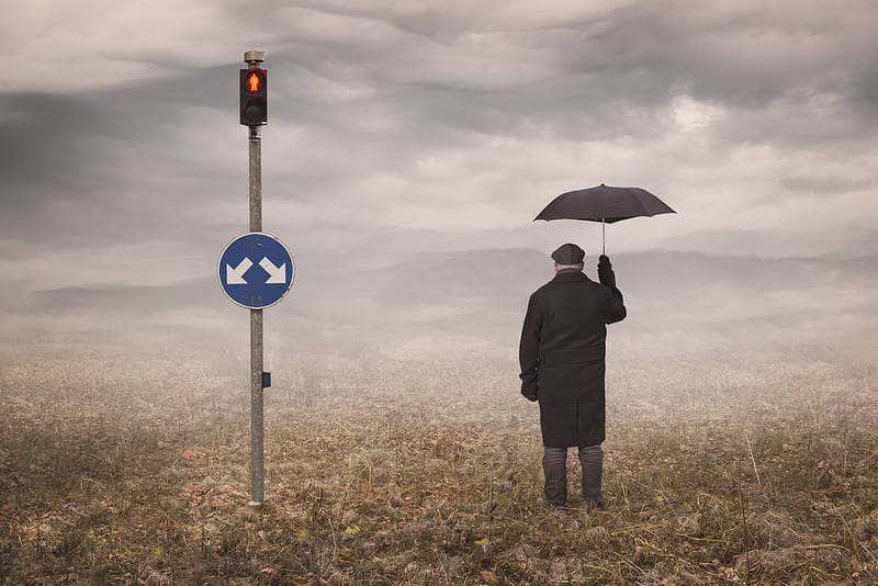 Man at crossroads with umbrella - Choicelessly choosing choicelessness