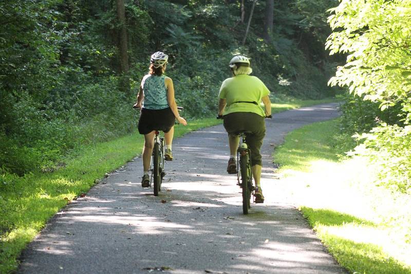 Middle-aged couple biking on paved trail - Becoming a master of healthy living