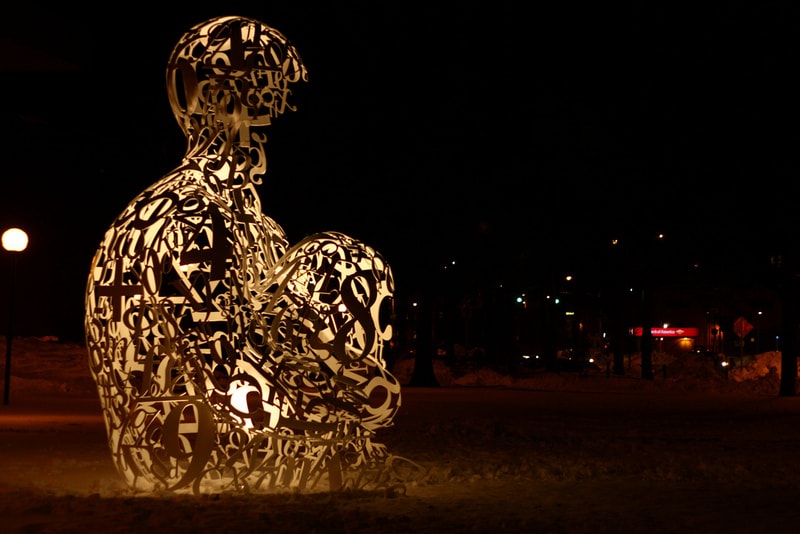 Sculpture of man sitting in park made from alchemy symbols