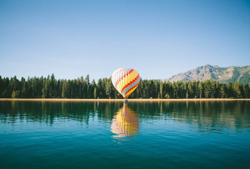 Hot air balloon floating just above lake - Liberation in wanting