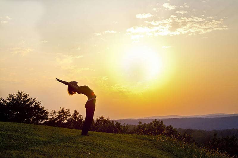 Woman doing yoga at sunrise - Poems by Neha Hewitt