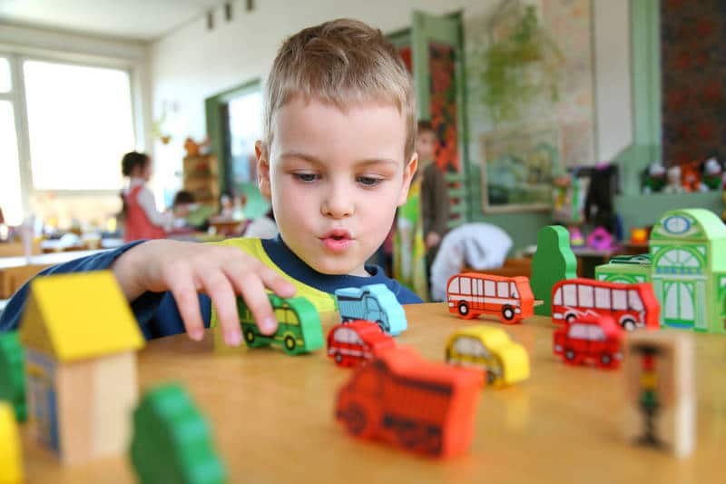 Little boy playing with toys on table - Confronting reality