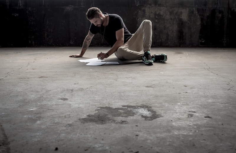 Man sitting alone on floor writing