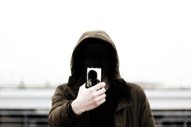 man in hoodie with selfie on a phone
