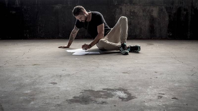 Man sitting on cement floor writing - Healing words