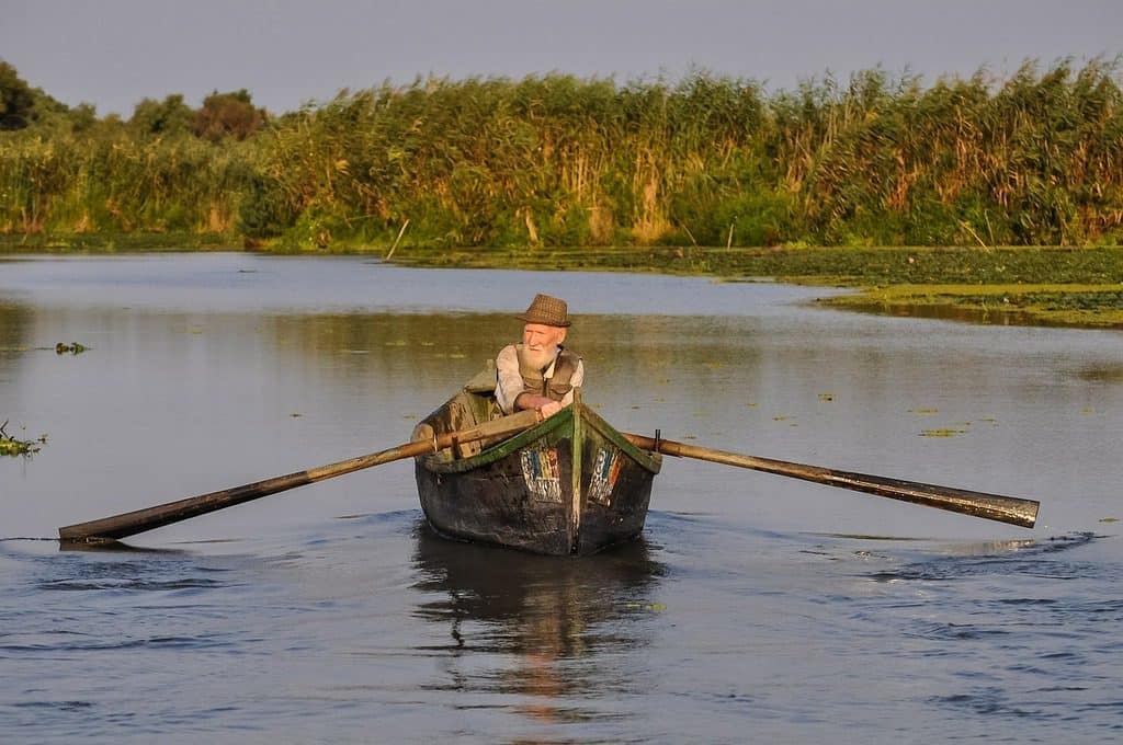 old man in rowing boat on river
