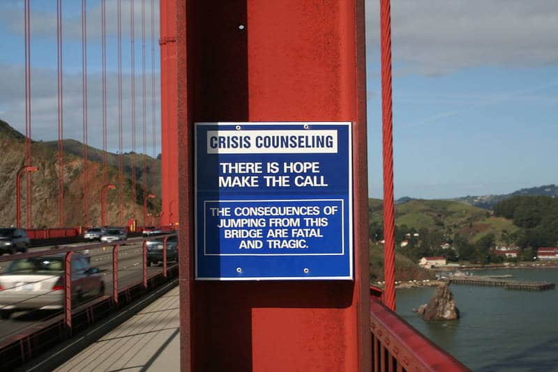 Bridge with crisis counselling sign for potential suicide attempts - Poems by John Grey