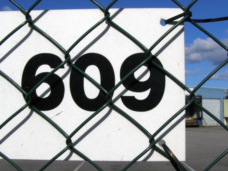 Number 609 on a piece of metal attached to fence