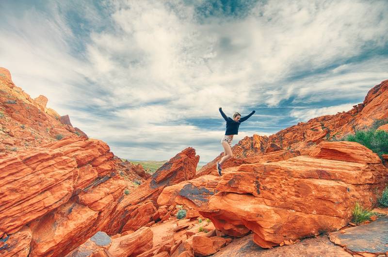 Young woman joyfully climbing rocks - The energy of yes
