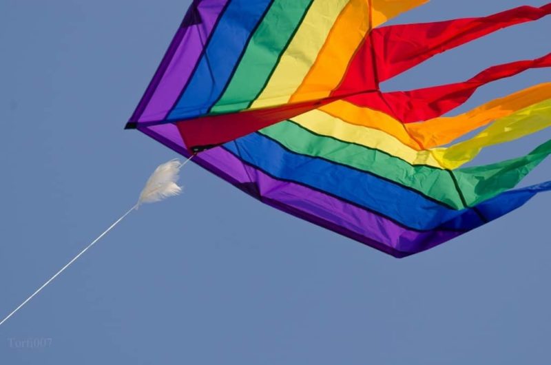 large rainbow coloured kite in the sky