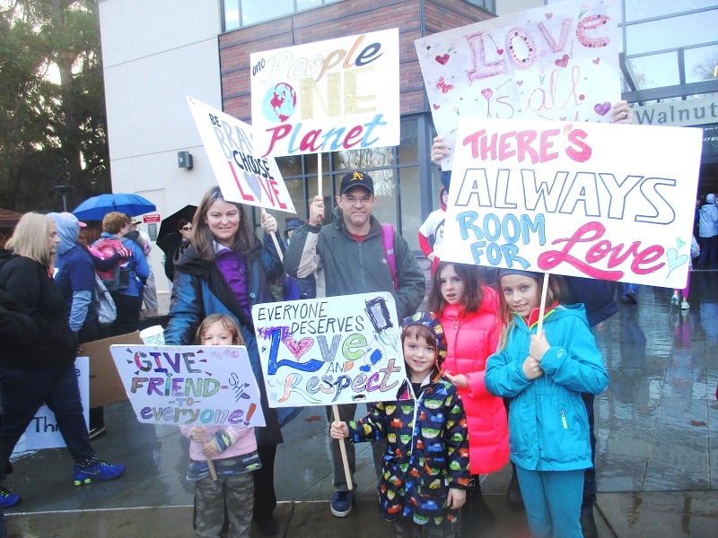 Family at Women's March holding positive, inspiring signs - After 9 months of Donald Trump