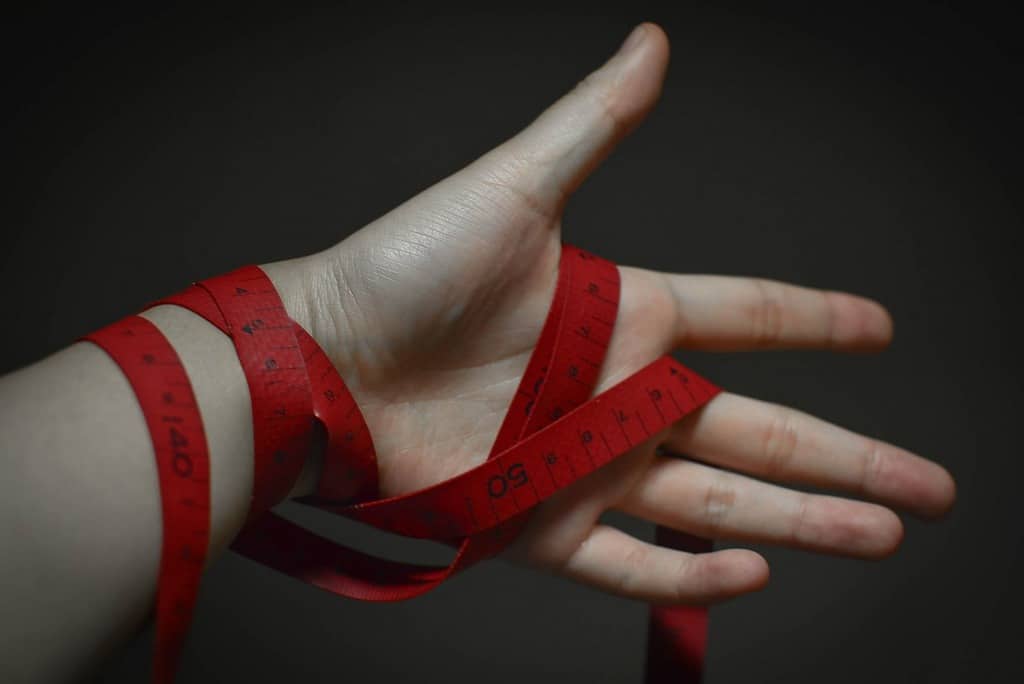 FIGHT YOUR EATING DISORDER: Without letting toxic New Year's resolutions get in the way 13 hand with tape measure wound around it