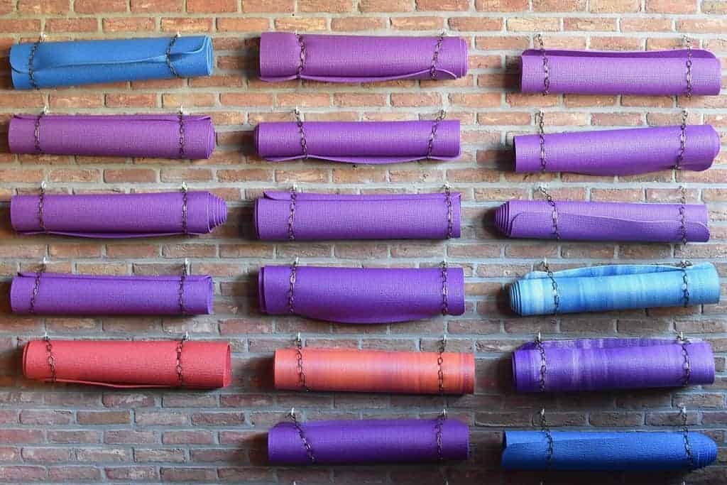 WHAT’S IN A MAT?: A lesson in Aparigraha—letting go 13 rolled yoga mats on a wall
