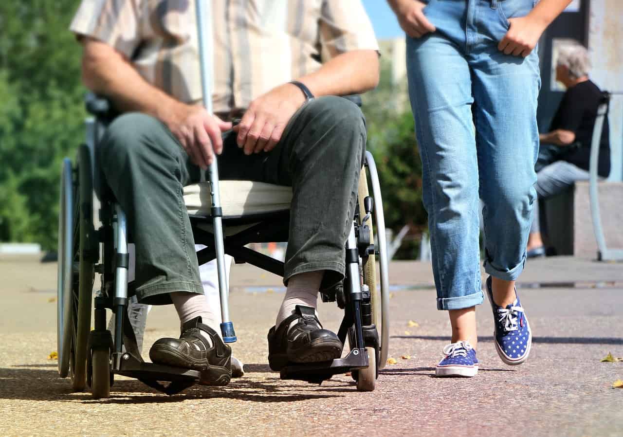 LONELY NO MORE: 5 ways that people with chronic pain can maintain a social life 16 Woman walking with man in wheelchair - Lonely no more