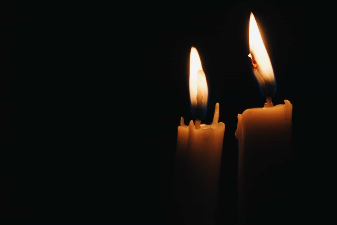 Two yellow candles against black background