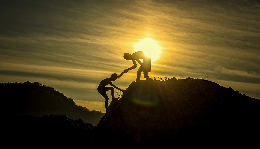 man helping another up a hill