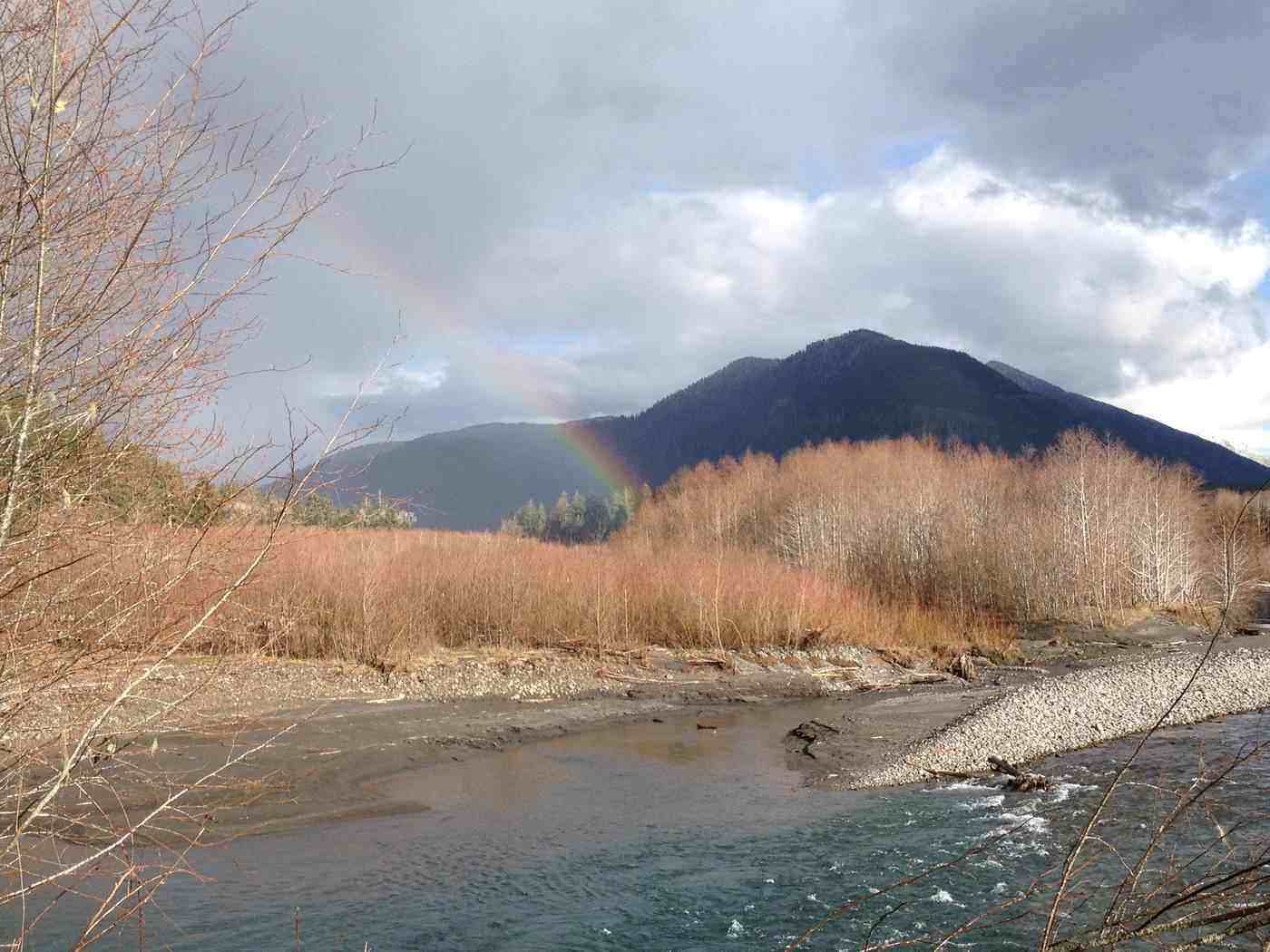 Rainbow against mountain, both next to water