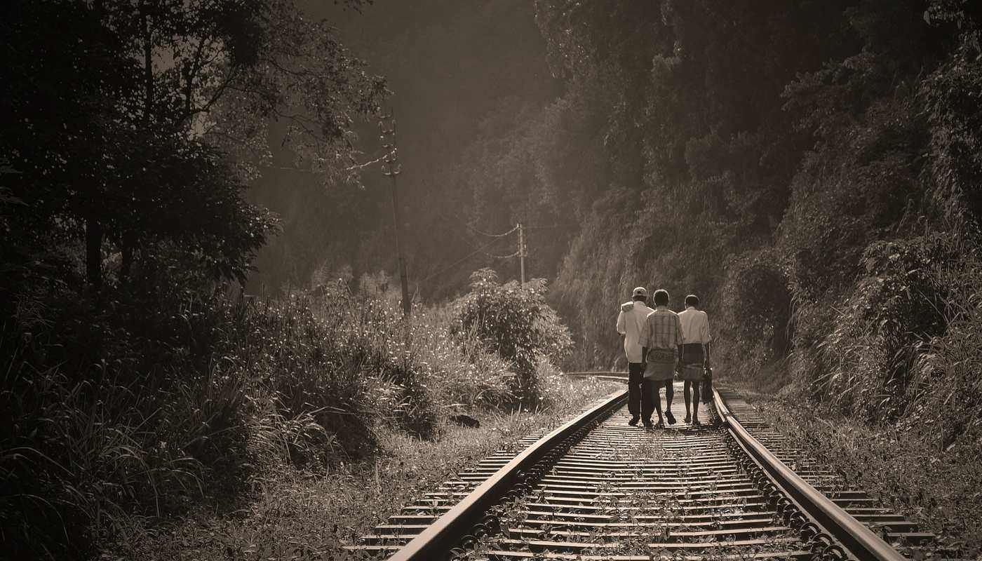 three people walking along a railway track