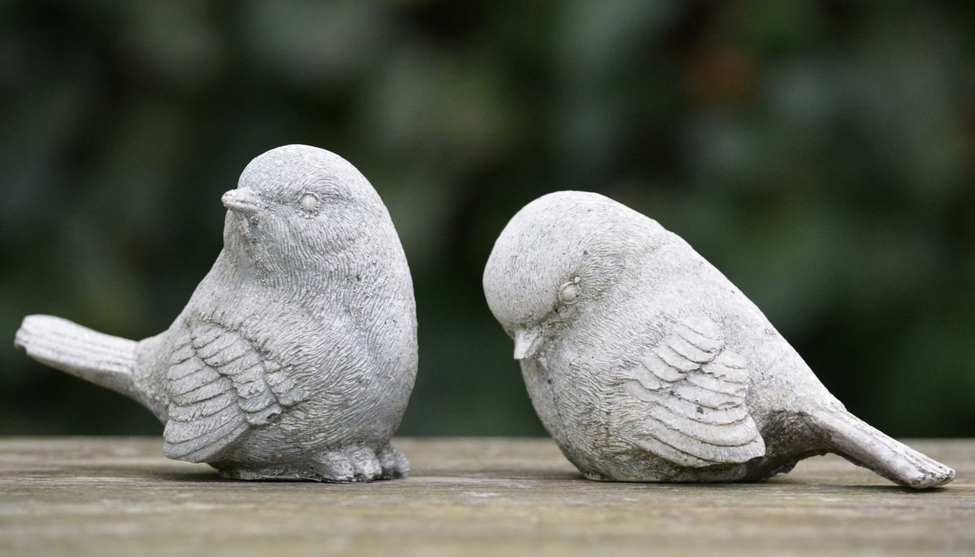 Two clay birds, one looking rejectied