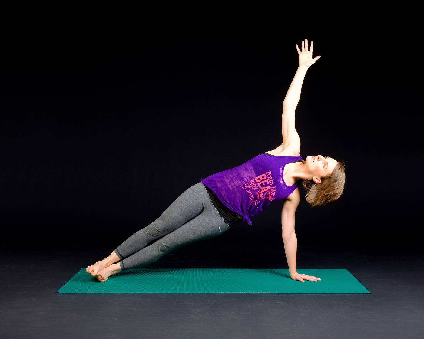 Woman doing side plank pose on Yoga mat