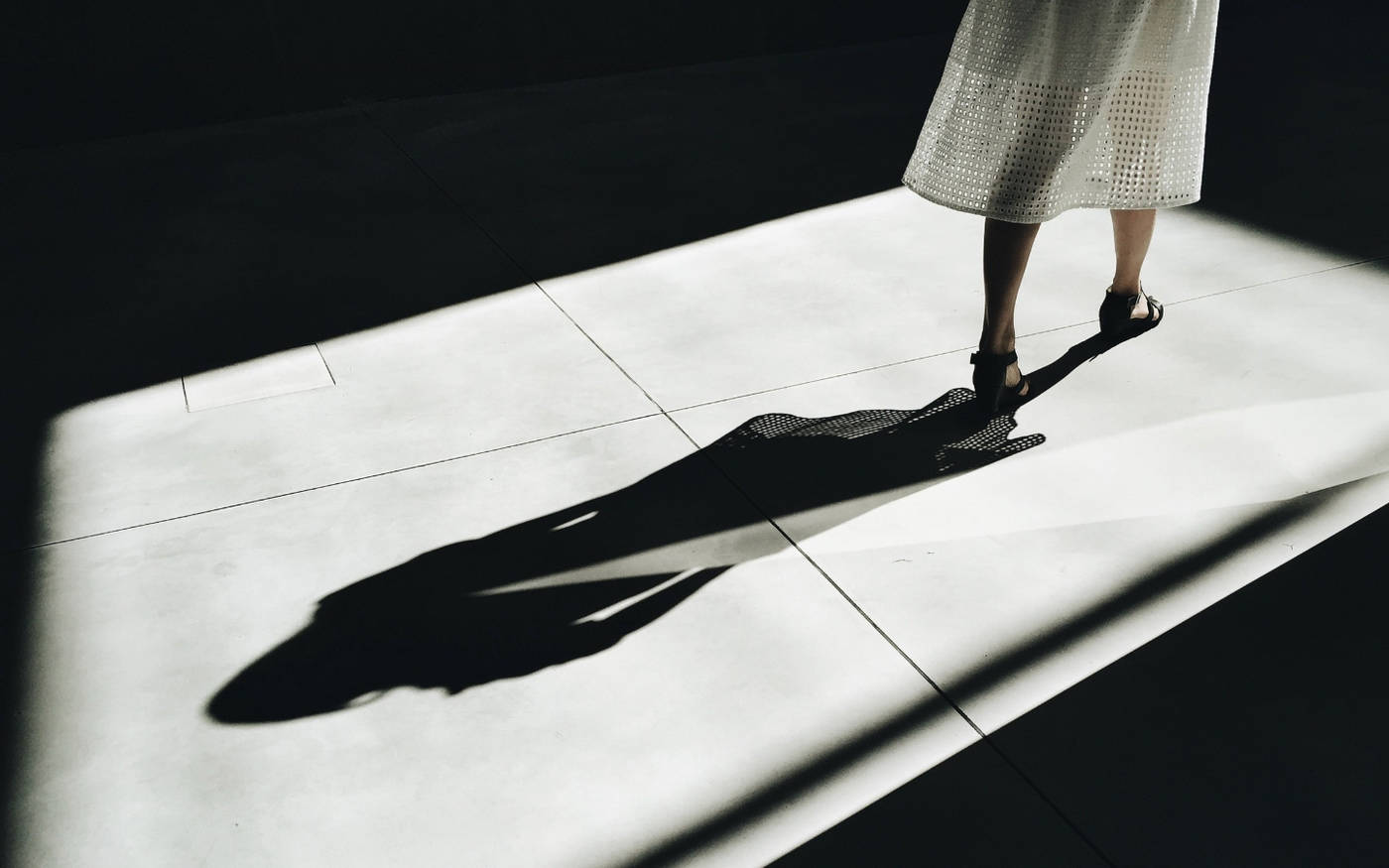 Woman walking in dress with shadow behind