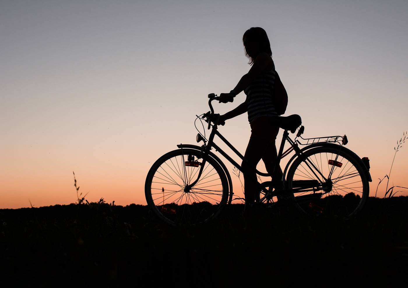 Silhouette of young woman next to bike