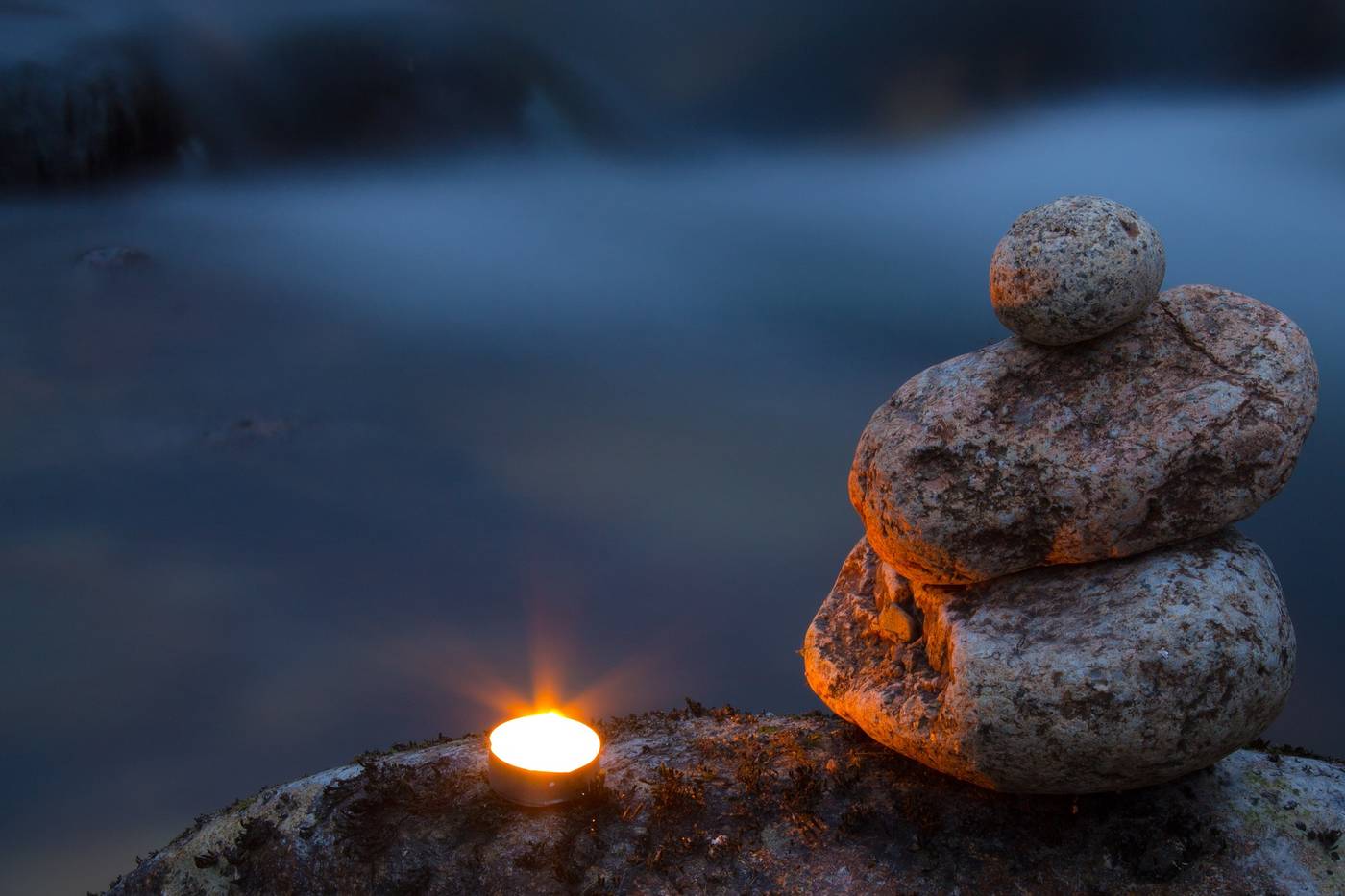 Lit candle next to Zen stones