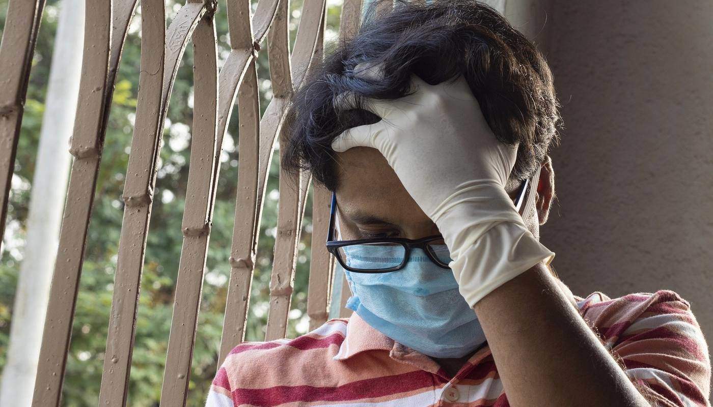 man with mask and surgical gloves behind fence