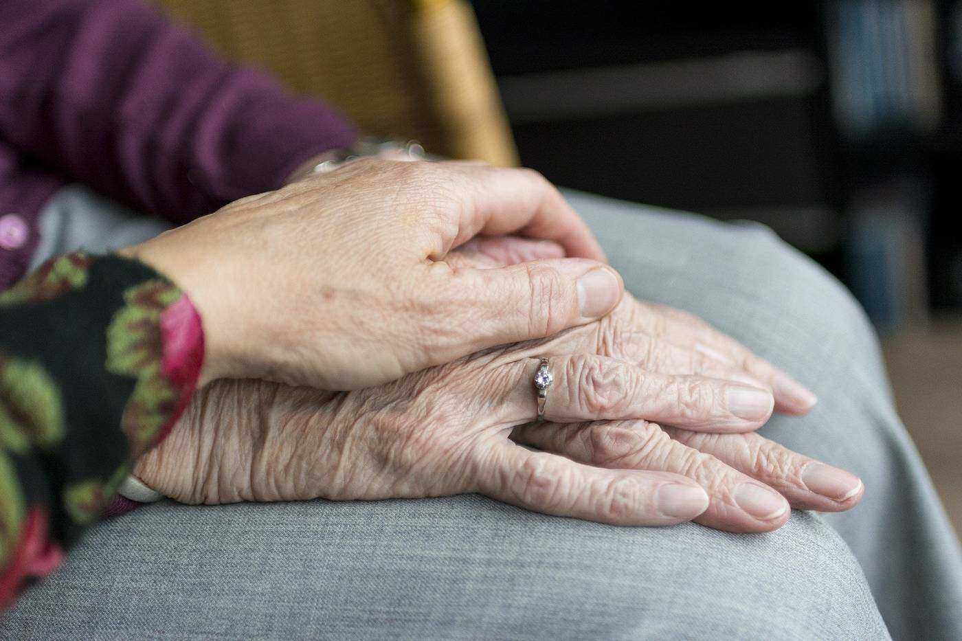 Younger woman holding senior woman's hand