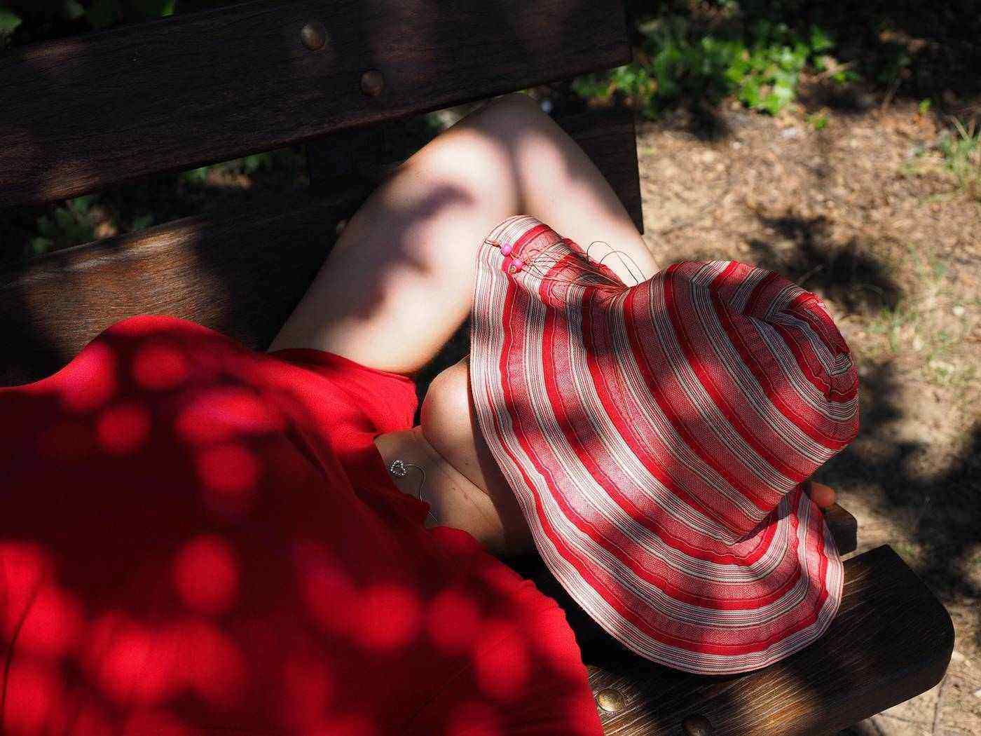 Woman sleeping on bench with hat over head