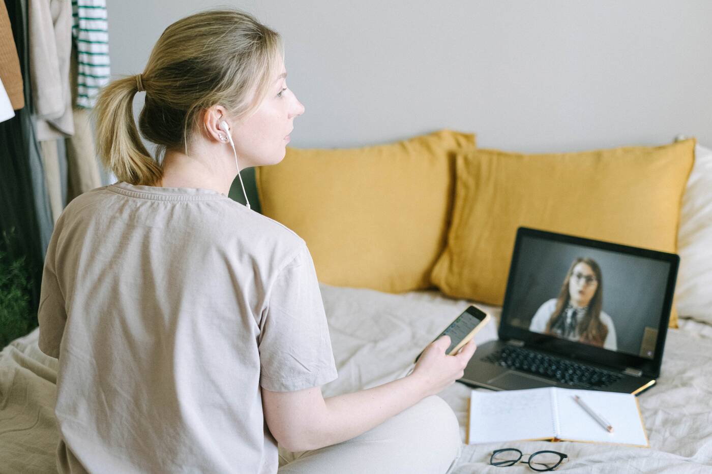 Woman on bed with laptop and phone