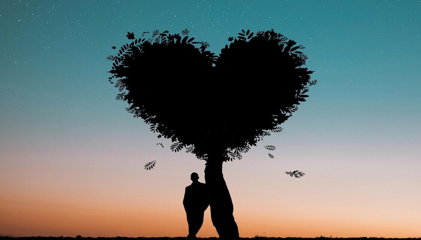 man leaning against heart-shaped tree