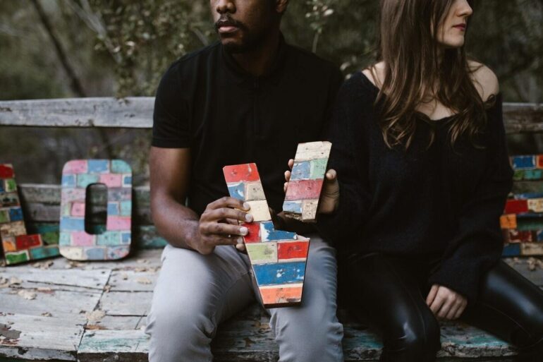two people on a park bench breaking the word love