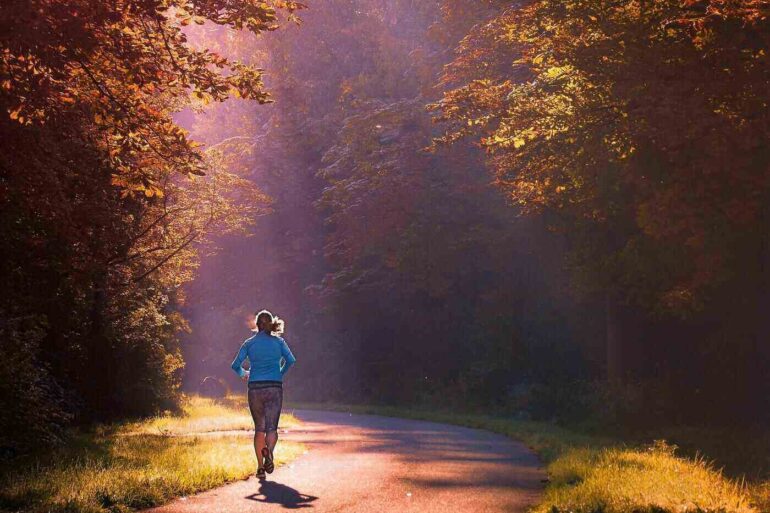 Woman running down country road in sun