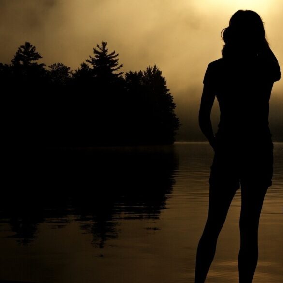 silhouette of girl on shore of lake