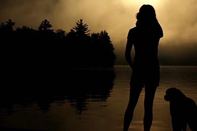 silhouette of girl on shore of lake