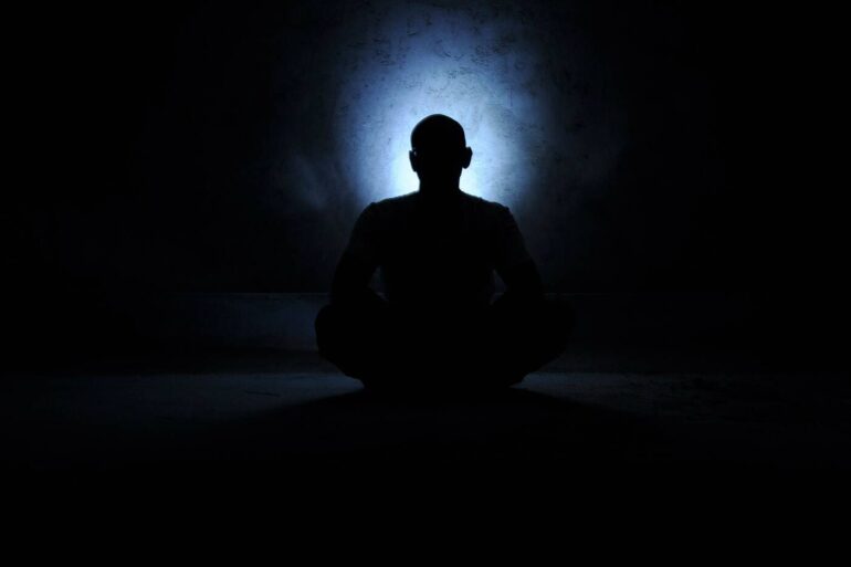Man meditating in dark, cavelike area