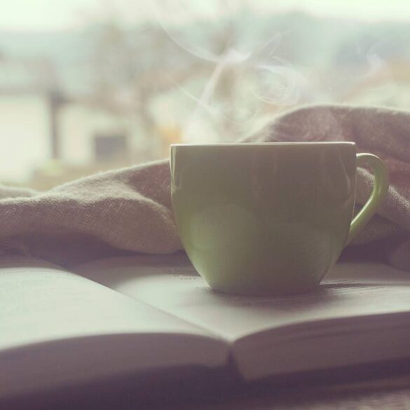 Steaming cup of coffee with book