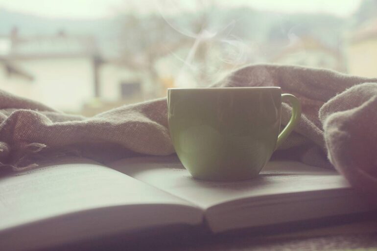 Steaming cup of coffee with book