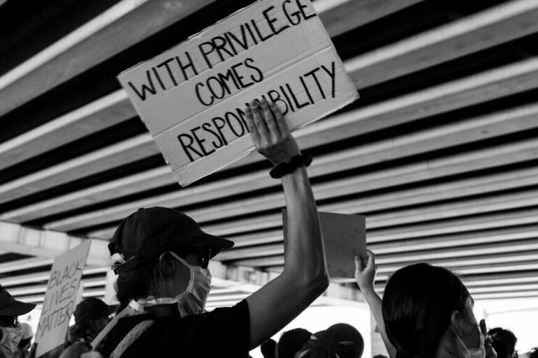 Crowd with sign with privilege comes responsibility