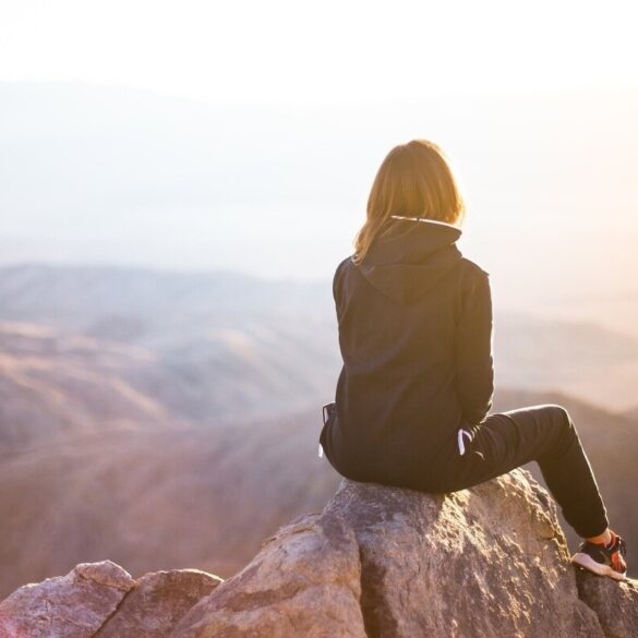 woman sitting on peak of a mountain